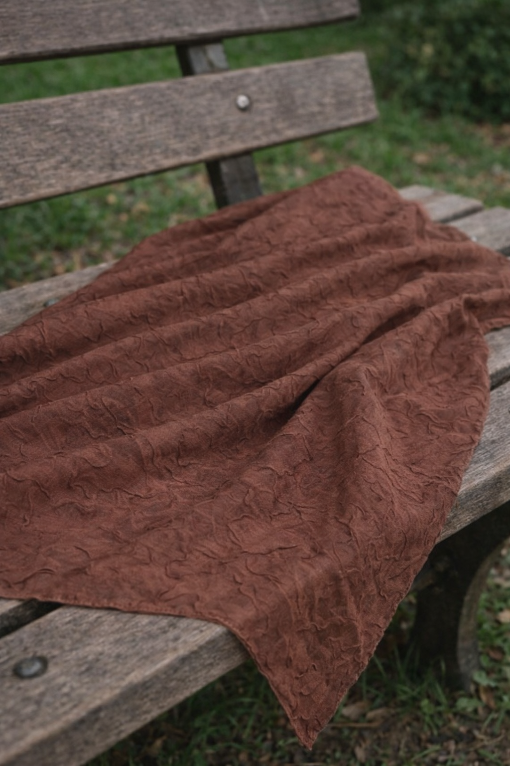 Hijab bambou marron chocolat déposé sur un banc en bois, dans un décor naturel, ambiance douce et chic. 