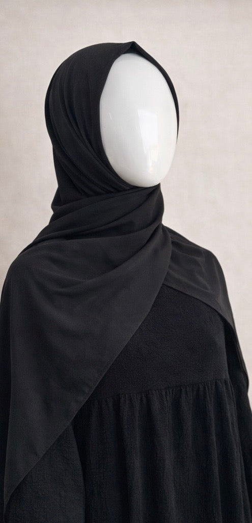 Hijab jersey noir profond porté sur mannequin, tissu fluide, style sobre et élégant