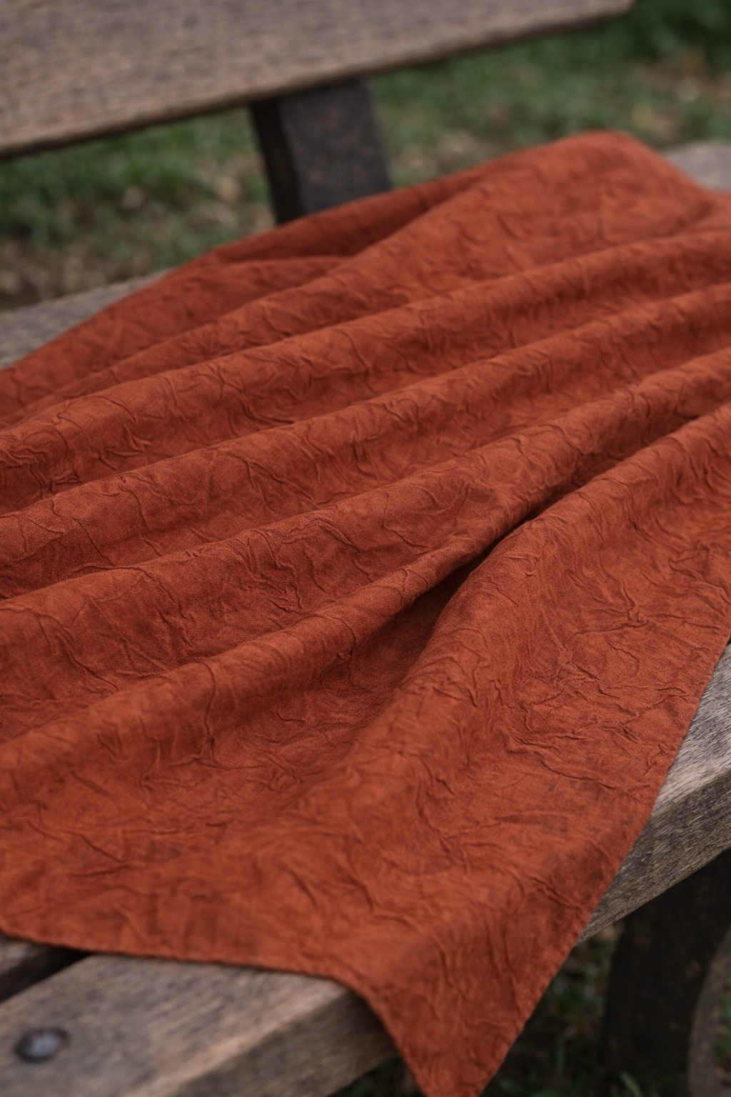 Hijab bambou orange délicatement posé sur un banc, en extérieur, lumière naturelle. 